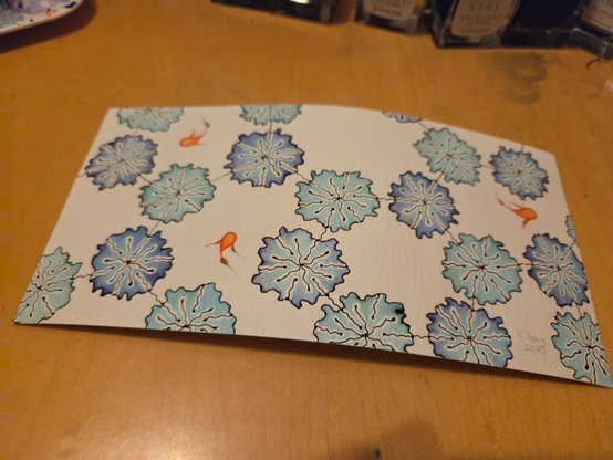 print of one of my drawings on my desk. the pattern is floral with three little orange fish.