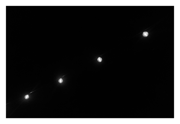 A string of four glowing light bulbs arranged in a diagonal line from the bottom left to the top right against a pitch-black background. A faint wire connecting the bulbs is barely visible. - Google Gemini 3 Pro Preview