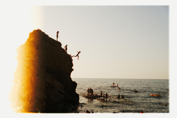 A photo of kid jumping from a cliff into the water captured in the very last moment.