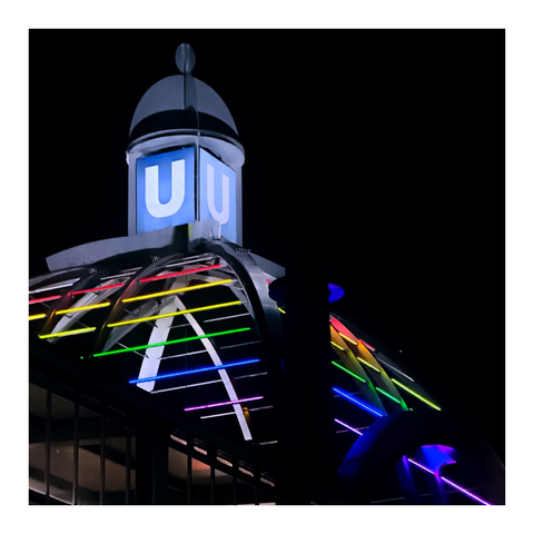 Dach einer U-Bahnstation mit U auf blau und regenbogenfarbenen Lichtstreifen in der Dunkelheit