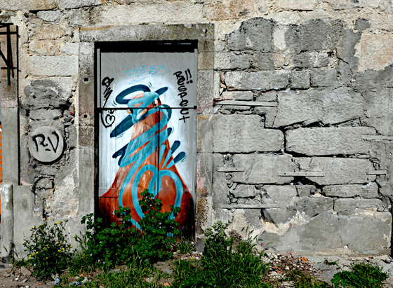 Foto van schildering van kleurige vogel en woord ‘respect’ op deur in oude muur