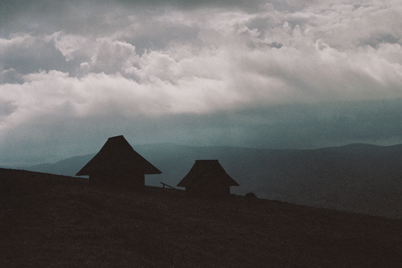 Two wooden houses before a storm in the mountains.