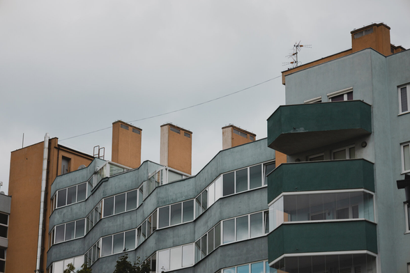 photo of a building during a gray day. the facade features light greenish-blue walls with orange accents