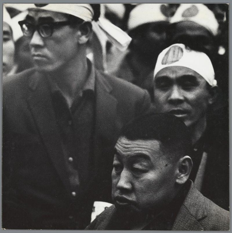 The image is a black and white photograph showing several individuals who appear to be part of an organized group or event. They are wearing similar headbands, which could suggest they belong to the same organization or movement. The expressions on their faces vary from serious to contemplative.

In terms of context provided by Knokploeg van een extreemrechtse, nationalistische organisatie (Group of a right-wing, nationalist organisation) in Tokio during 1959-60 by Ed van der Elsken, it can be inferred that these individuals are likely associated with Japanese extreme-right or nationalist groups active around the late 1950s and early 1960s. The photograph captures a moment of their gathering, possibly for a rally or public demonstration.

Ed van der Elsken was known for his work in documenting various aspects of life during mid-20th century Japan, including its social dynamics and political movements. This specific image contributes to the historical record by offering insight into the presence and expression of right-wing nationalism within Tokyo at that time.
