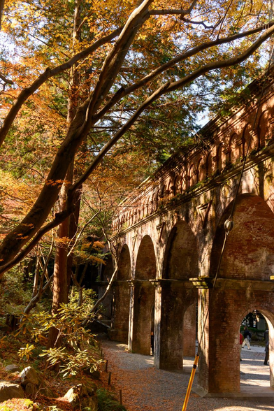 1枚目の写真から少し東。やや赤めのイロハモミジと水路閣。赤いイロハモミジから溢れる光や影の影響か、水路閣もやや赤みを帯びて見える。/ 2025.12.07 南禅寺から 