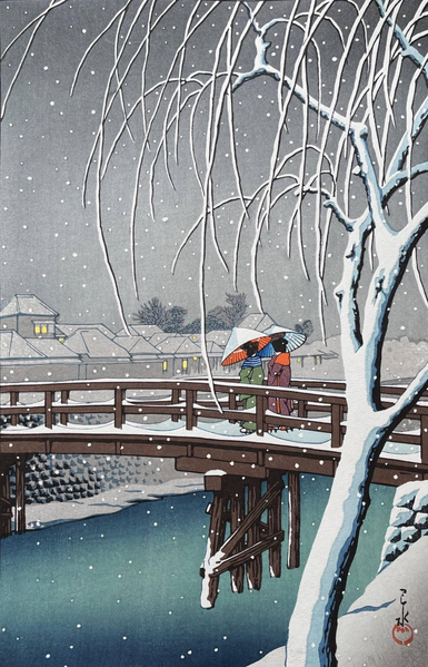 A winter evening in Tokyo, overlooking the Edo River. In the foreground, the trunk and wiry branches of a leafless tree are rimed with snow and frost; beyond, two women carrying bamboo umbrellas cross a gently curving wooden bridge. Below the pedestrians, the river is still and cold-looking. On the far side of the water, warm lights shine in the windows of closely-packed houses. The sky above is grey and overcast, and snow continues to fall across the scene.