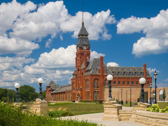 A great red brick Victorian building with a clock tower in a park as this area is now a park