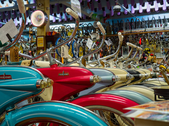 A row of vintage streamlined Bowden bikes of different colors: cyan, red, light blue, cream, and black. The red one catches my attention.