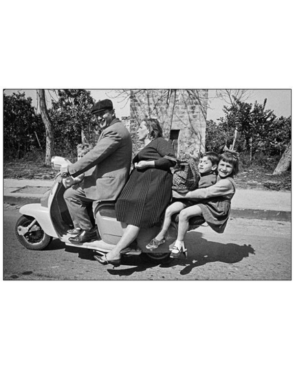 BW pic of a 4 people family riding on one Vespa.