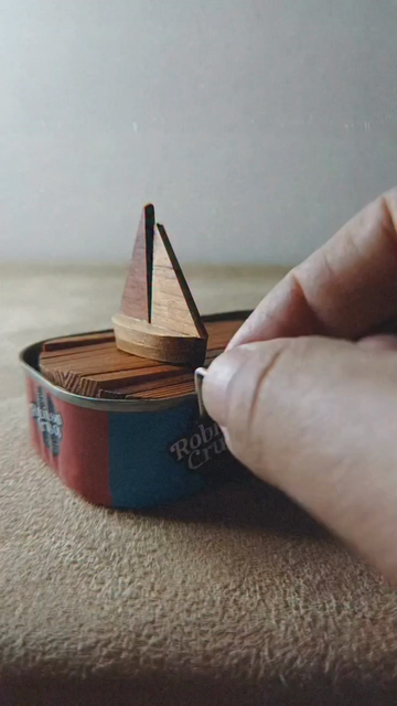 un petit voilier de bois voguant sur les flots agités à la manivelle d’une vieille boite de conserve de sardines