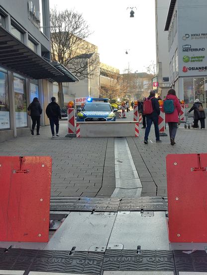 Einsatzfahrzeug mit Blaulicht vor Schutzblockade in der Fußgängerzone