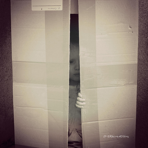 Mon fils alors âgé de 2 ou 3 ans, caché dans un grand carton. On ne voit que sa main et une partie de son visage.