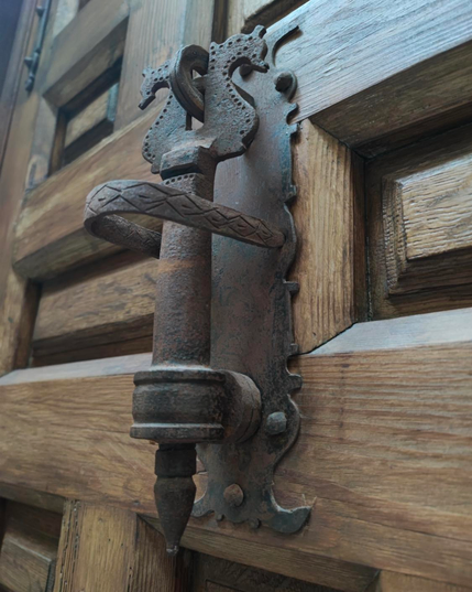 The top of the knocker features two seahorses facing away from each other. The backplate has a sawtooth or "scalloped" edge.