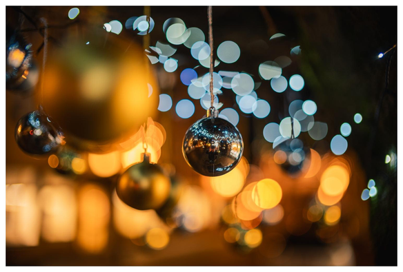 Silberne Christbaumkugel an Baum hängend vor Bokehball-Armee.