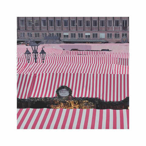 overlooking the textile roofscape of a christmas market. the textiles are painted in red and white stripes. some lamp posts are sticking out, in the background some buildings surrounding the market appear