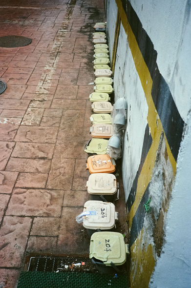 작은 음식물쓰레기 통이 벽을 따라 일렬로 늘어서듯 놓여있다. 통이 만들어낸 '선'을 세로로 보이게 찍었다.