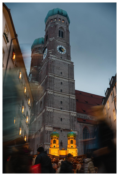 Eine Glühweinbude mit einem Modell der Doppeltürme der Frauenkirche in München steht vor dem Original. 