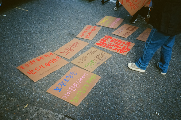 집회 전, 아스팔트 도로에 각종 구호를 쓴 골판지가 정렬되어 있다. “굽힘 없이 투쟁하여 반드시 승리한다”, “보광소장은 기아원청 뒤에서 청소비정규직 착취 말라”, “기아원청이 부당해고·징계 철회해”, “노동해방”, “노동자 착취는 친환경이 될 수 없다. 기아차는 각성하라”, “기아차가 책임져”, “기아원청 숨지말라 앞장서서 해결하라”, “원하청 총단결로 노동탄압 박살내자”, “해고는 '살인'이다!”, “노란봉투법 엄살말고 노동탄압 중단하라”, “기아원청이 책임져!”, “부당해고 철회! 노동탄압 분쇄!” 등이 적혀있다.