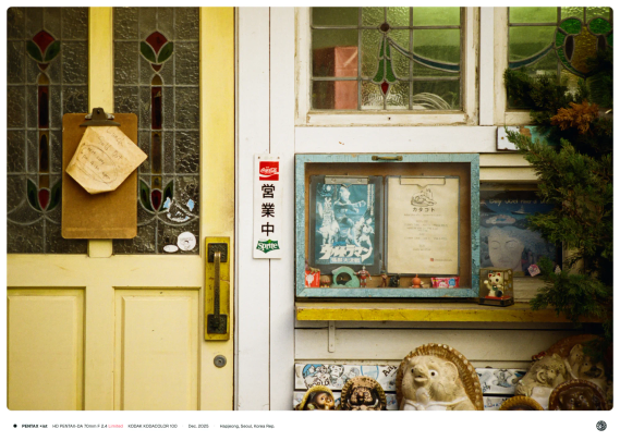 가게의 정문, 좌측 노란 문 중앙에는 클립보드에 'Lunch Sold Out'이 써 있고, 중앙에는 일본어로 영업중(営業中) 팻말이, 우측에는 옛날 일본 포스터나 소품 등이 전시되어 있다.