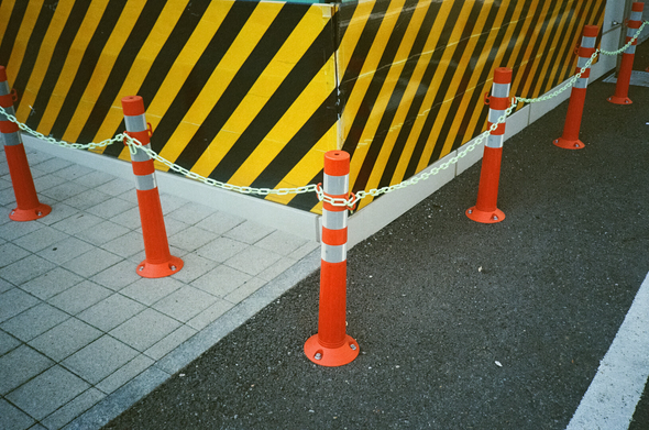 노란색·검정색 주의색으로 덮힌 구조물 모서리를 따라 붉은색 고무 볼라드가 세워져있고, 볼라드마다 빛바랜 형광색 플라스틱 사슬이 걸려있다.