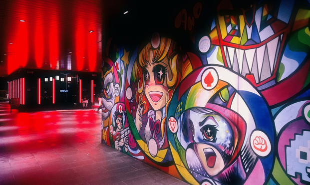 A colourful wall mural decorates a hotel entrance. The entrance is surrounded by red light strips.