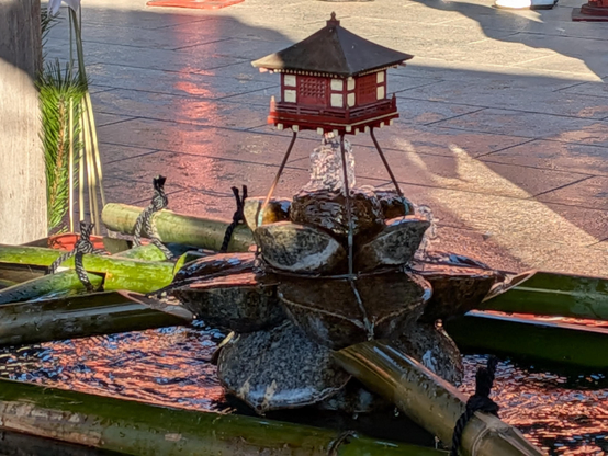 Ein kleines Wasserspiel mit einem Tempelgebäude als Modell.
Von einem Brunnen um die Hände zu reinigen.