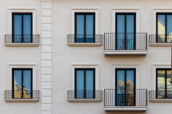 Español: fotografía donde se ve una fachada blanca con varias ventanas que reflejan un cielo azul y algunos detalles arquitectónicos de la ciudad.


English: photograph showing a white facade with several windows reflecting a blue sky and some architectural details of the city.
