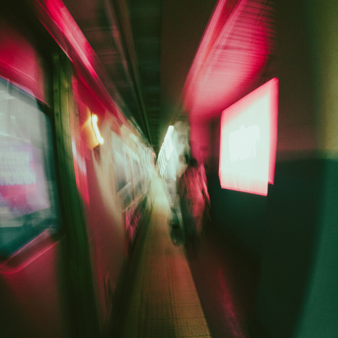 Blurry image of a train platform with a woman walking with a bag in the middle of the frame.