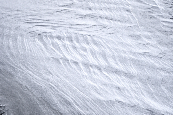 Das Foto zeigt eine schneebedeckte Fläche, die durch Wind und natürliche Einflüsse geformt wurde. Im Schnee sind interessante Muster und Strukturen zu erkennen: wellenartige Linien und sanfte Kurven, die an Dünen erinnern. Es wirkt, als wäre der Schnee vom Wind glatt geschliffen worden, was dem Bild eine fast künstlerische, abstrakte Qualität verleiht.
 -------- 
The photo shows a snow-covered area that has been shaped by wind and natural forces. Interesting patterns and structures can be seen in the snow: wave-like lines and gentle curves reminiscent of dunes. It looks as if the snow has been smoothed by the wind, giving the image an almost artistic, abstract quality.