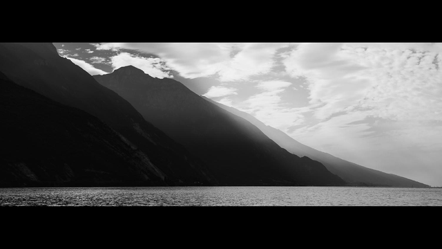 Schwarz-Weiß Aufnahme von einer Bergkette an einem See im X-Pan Format. Die Berge erzeugen mit dem Dunst einen recht starken Effekt von Tiefe und Drama, Baby!
