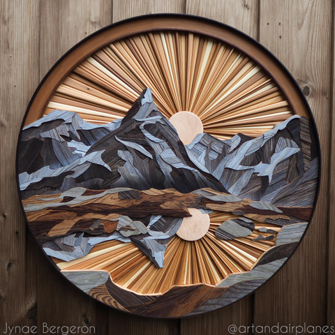 Circular wooden artwork depicting a mountain range in Norway featuring a sunburst sky and a reflection scene.