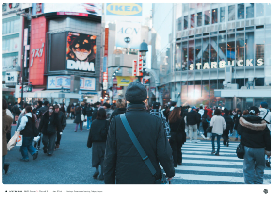 시부야 스크램블 교차로에서 한 노인이 인파 속에서 거대한 건물들을 마주한 채 횡단하고 있는 모습.