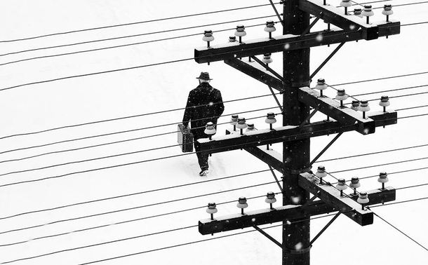 la position de l’homme comme une noire en manteau d’hiver sur la portée musicale des lignes téléphoniques, valant un temps dans une mesure chiffrée 4/4