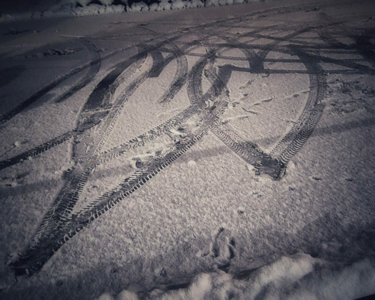 Tyre tracks on a snow covered parking lot, resembling two intertwined hearts