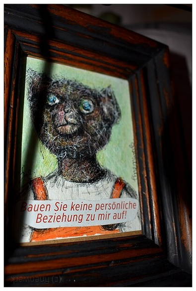Farbfoto auf dem ein gezeichnetes Teddybärenportrait in einem dunklen Holzrahmen zu sehen ist. Im unteren teitl des Bildes Steht auf weißen Grund in roten Buchstaben: Bauen Sie keine persönliche Beziehung zu mir auf! 