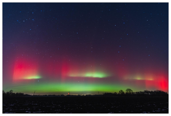 Polarlichter (rot/grün) im Nachthimmel.