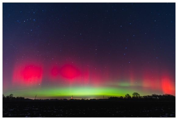 Polarlichter (rot/grün) im Nachthimmel.