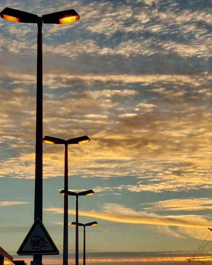Vier Laternen mit Doppel-Lampe stehen im Sonnenuntergang an einem Bahnsteig. Der Himmel glüht golden, orange, violett und blau, die Laternen leuchten ihr schönstes oranges Licht. Nä, watt isset doch schön!
// 
Four double-lamp lanterns stand on a platform at sunset. The sky burns golden, orange, purple and blue, and the bold lanterns glow orange. Oh, this is sooo romantic!