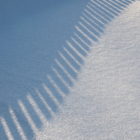Shadow of a fence on white snow.
