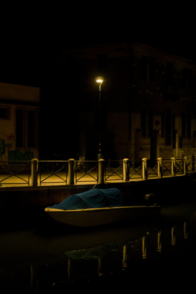 By the quiet bank, under the night, on black water, a boat waits in light.