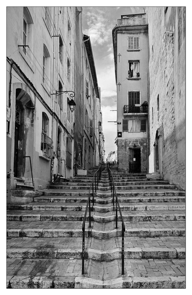 Steep stairs in an old town. Old town houses on the right and left. In the middle, an iron stair railing. 