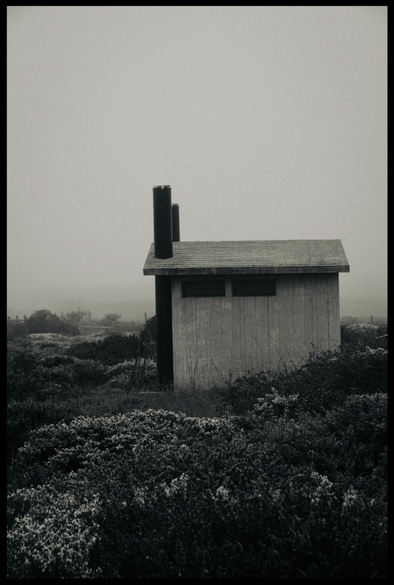 Yes, it's Sunday and I am pretending to be Ansel Adams. This outhouse is my Half Dome.

Taken on a foggy morning at an ungodly hour, this sturdy, nearly featureless concrete building stands in profile in a field of brush and scrubby weeds underneath unrelenting gray skies. With two tiny windows, a slightly pitched roof, and two vent pipes / chimneys, this is a building without cheer, set in a landscape of bleakness and cold. The despair is evident. There is no cell phone reception and the nearest coffeeshop is 15 miles away.

Monochrome.