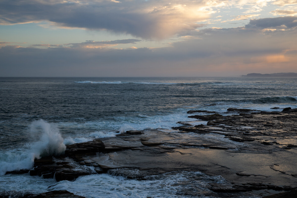 A photo looking across the Bouddi Point rockshelf out to sea, taken near sunset.
