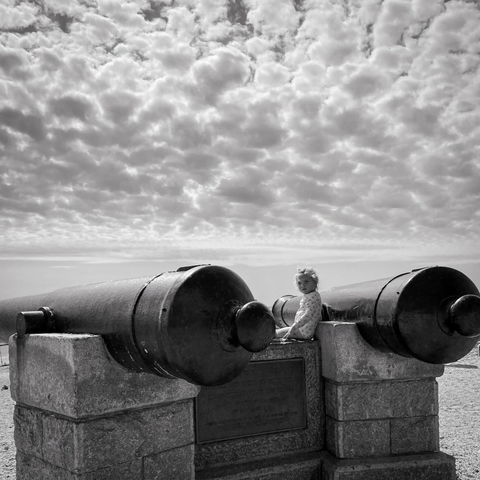 petite fille assise entre deux gigantesques canons pointant vers la plage de Compo, commémorant la bataille de Westport entre les forces britanniques et les patriotes américains, le 28 avril 1777
