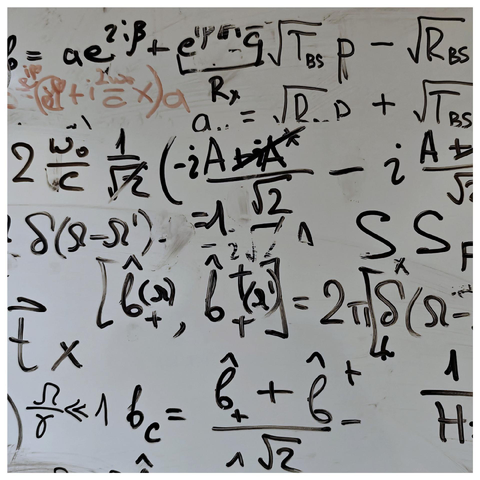 A photo of a slightly messy whiteboard covered with handwritten mathematical equations and symbols.
