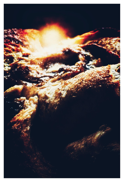 Closeup of the lumpy and textured surface of a loaf of sourdough cinnamon bread, edited to look like shadowy mountains and valleys edged with golden light from a distant sunrise.