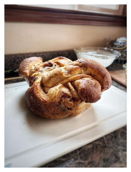 The entire loaf of cinnamon bread, seen as is, on a kitchen counter. It’s bursting out of its glass baking dish, swelling up and flowing over the edges in great lumps and folds. Not quite what the baker intended, but it was delicious all the same.