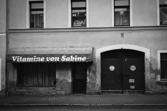 An einer Fassade ist ein ehemaliger Laden erkennbar mit dem Schriftzug „Vitamine von Sabine“
