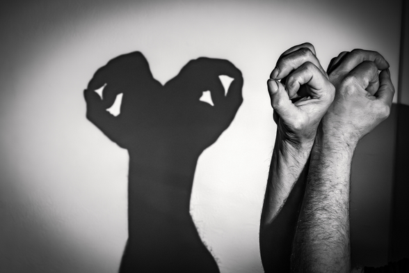 Das Schwarz-Weiß-Foto zeigt zwei Hände, die eine skurrile Schattenfigur an einer Wand erzeugen, die der fiktiven Figur E.T, der Außerirdische ähneln.