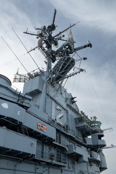 A complex slate-gray structure rises high above the deck of an aircraft carrier.